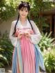 A woman in a pink and blue hanbok is posing for a picture.