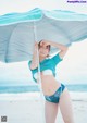 A woman in a bikini holding an umbrella on the beach.