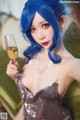 A woman with blue hair holding a glass of wine.